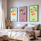 Set of 3 framed canvas triptych featuring soft watercolor botanical illustrations of pear, fig and apple branches with Arabic calligraphy labels on pastel mint, pink and green backgrounds, displayed above a neutral sofa.
