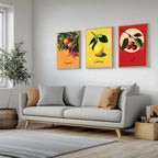 Set of 3 framed canvas triptych featuring bold retro illustrations of orange, lemon and cherry with Arabic calligraphy labels on vibrant orange, yellow and red backgrounds, displayed above a neutral sofa.