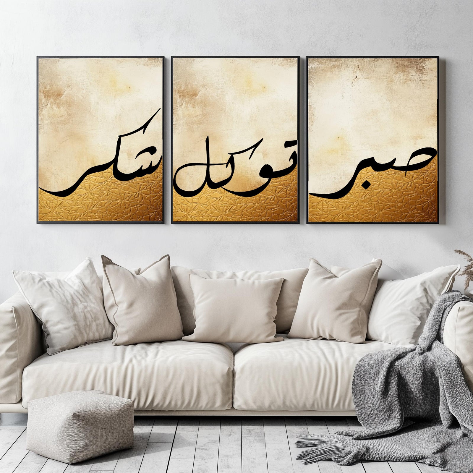 Set of 3 framed canvas triptych featuring Shukr, Tawakkul and Sabr in bold black Arabic calligraphy on a warm amber and cream textured background, displayed above a neutral sofa in a modern living room.