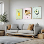 Set of 3 framed canvas triptych featuring illustrated olive oil bottle, flatbread and labneh bowl with Arabic calligraphy labels on soft green, pink and blue pastel backgrounds, displayed above a neutral sofa.