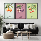 Set of 3 framed canvas triptych featuring soft watercolor botanical illustrations of pear, fig and apple branches with Arabic calligraphy labels on pastel mint, pink and green backgrounds, displayed above a neutral sofa.