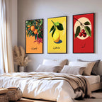 Set of 3 framed canvas triptych featuring bold retro illustrations of orange, lemon and cherry with Arabic calligraphy labels on vibrant orange, yellow and red backgrounds, displayed above a neutral sofa.