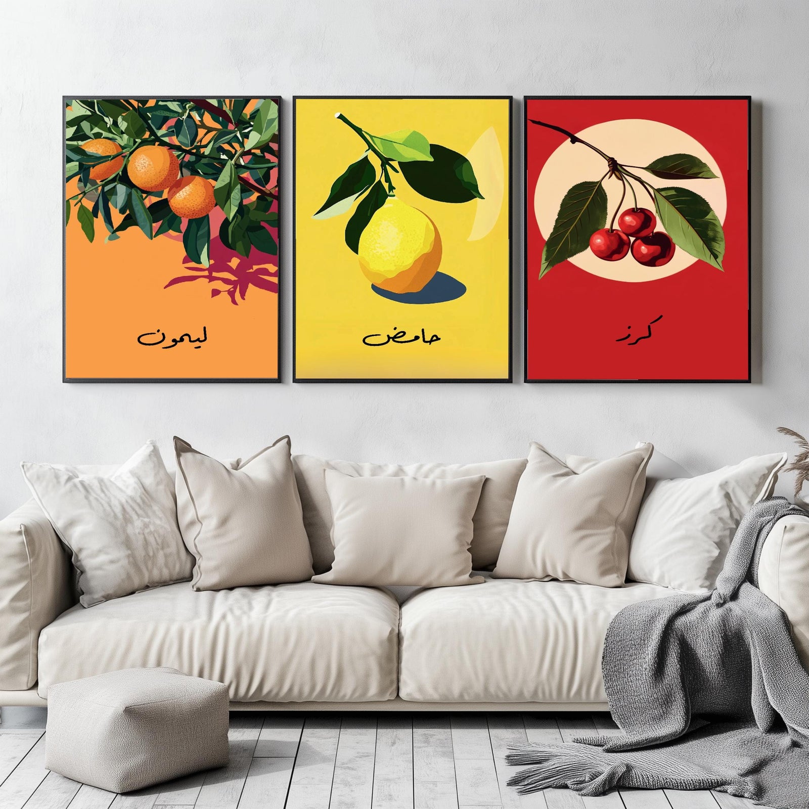 Set of 3 framed canvas triptych featuring bold retro illustrations of orange, lemon and cherry with Arabic calligraphy labels on vibrant orange, yellow and red backgrounds, displayed above a neutral sofa.