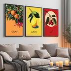 Set of 3 framed canvas triptych featuring bold retro illustrations of orange, lemon and cherry with Arabic calligraphy labels on vibrant orange, yellow and red backgrounds, displayed above a neutral sofa.