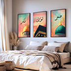 Set of 3 framed canvas triptych with Shukr, Tawakkul and Sabr in Arabic calligraphy above close-up mosque domes against a dreamy coral and teal sunset sky, displayed above a neutral sofa in a modern living room.