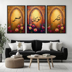Set of 3 framed canvas triptych with Sabr, Shukr and Tawakkul Arabic calligraphy inside golden Islamic arches, rich red and amber tones with painted roses, displayed on a warm neutral wall above a grey sofa.