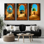 Set of 3 framed canvas triptych depicting the Dome of the Rock, the Kaaba and Al-Masjid An-Nabawi viewed through warm stone arches in a rich painterly style, displayed above a neutral sofa in a modern living room.
