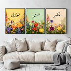 Set of 3 framed canvas triptych with Tawakkul, Sabr and Shukr in Arabic calligraphy above vibrant wildflower gardens on pastel yellow, green and peach backgrounds, displayed above a neutral sofa.