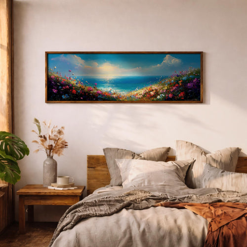 Panoramic coastal landscape painting showing colorful wildflowers blooming along a seaside cliff overlooking a calm blue ocean. Bright floral brushstrokes in pink, purple, yellow, and red frame the foreground while sunlight glows over the horizon and soft clouds stretch across the open sky above the tranquil water.
