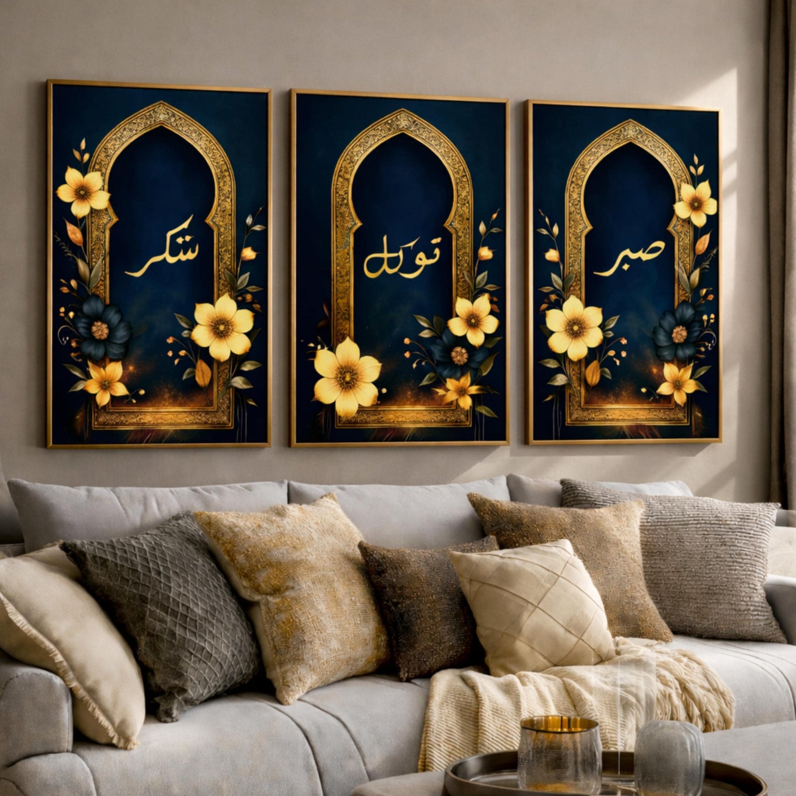 Set of 3 framed canvas triptych with Sabr, Shukr and Tawakkul in gold Arabic calligraphy inside ornate navy and gold Islamic arches surrounded by yellow and dark blue flowers, displayed above a grey sofa.