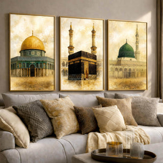 Set of 3 framed canvas triptych depicting the Dome of the Rock, the Kaaba and Al-Masjid An-Nabawi in a soft antique sepia and gold manuscript style, displayed above a neutral sofa in a modern living room.