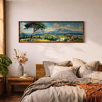 Panoramic impressionist landscape painting of the Tuscan countryside with a leaning pine tree in the foreground overlooking rolling green and golden fields. A small Italian village with terracotta rooftops sits beneath distant blue mountains while textured brushstrokes capture bright skies, cypress trees, and the sunlit rural scenery.