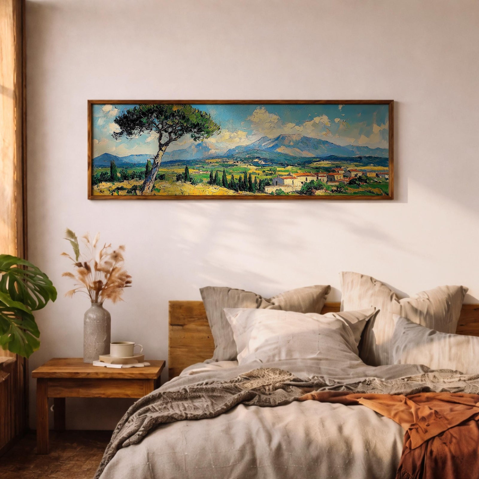 Panoramic impressionist landscape painting of the Tuscan countryside with a leaning pine tree in the foreground overlooking rolling green and golden fields. A small Italian village with terracotta rooftops sits beneath distant blue mountains while textured brushstrokes capture bright skies, cypress trees, and the sunlit rural scenery.