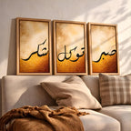 Set of 3 framed canvas triptych featuring Shukr, Tawakkul and Sabr in bold black Arabic calligraphy on a warm amber and cream textured background, displayed above a neutral sofa in a modern living room.