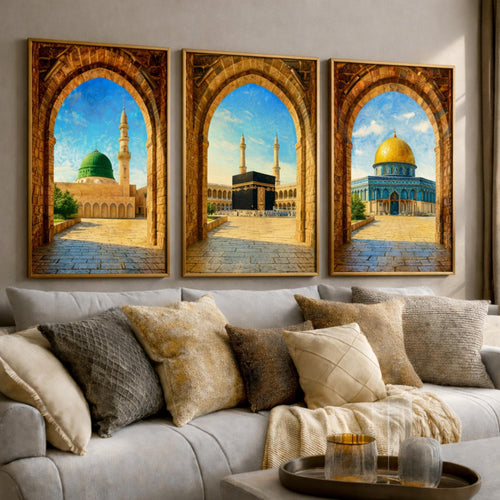 Set of 3 framed canvas triptych showing Al-Masjid An-Nabawi, the Kaaba and the Dome of the Rock viewed through realistic rustic sandstone arches with cobblestone courtyards under a bright blue sky, displayed above a neutral sofa.