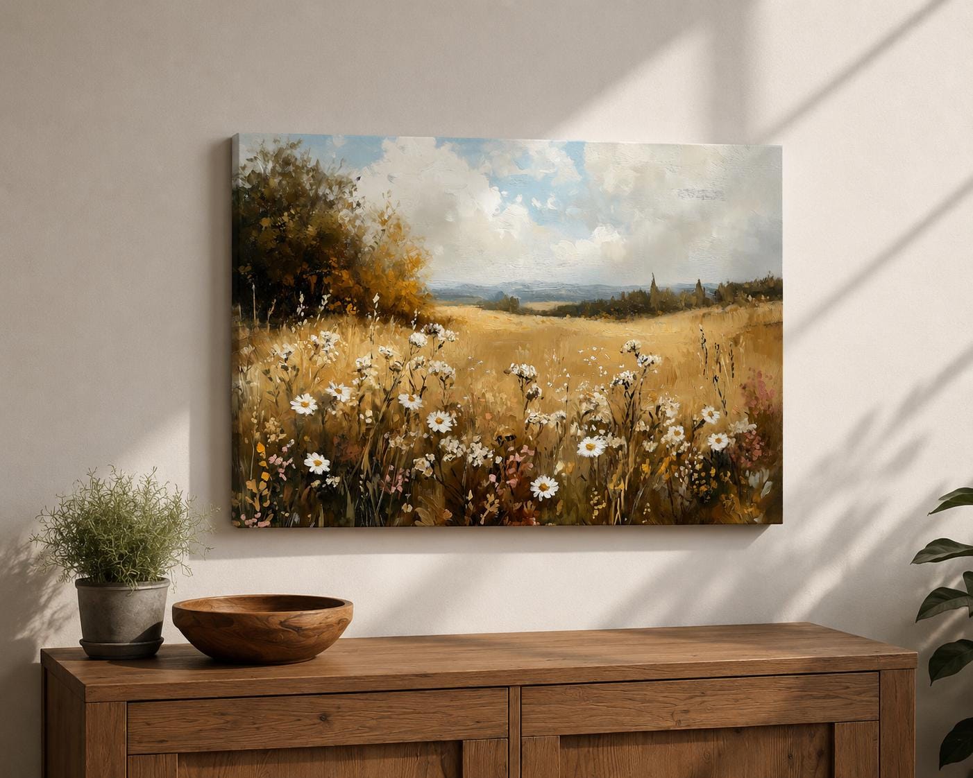 A vintage-style framed canvas painting of a wildflower meadow featuring white daisies and tall grasses under a cloudy sky. The landscape composition highlights a rustic field bordered by trees with distant hills, rendered in warm earthy tones and textured brushwork.