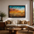 A framed canvas painting depicting a wheat field at sunset with golden stalks swaying under a vibrant sky blending orange, yellow, and blue hues. The artwork captures a rustic farmhouse landscape scene with textured brushstrokes emphasizing natural elements and an expansive horizon.