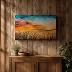 A framed canvas painting depicting a wheat field at sunset with golden stalks swaying under a vibrant sky blending orange, yellow, and blue hues. The artwork captures a rustic farmhouse landscape scene with textured brushstrokes emphasizing natural elements and an expansive horizon.