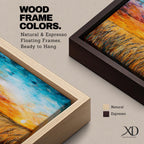 A framed canvas painting depicting a wheat field at sunset with golden stalks swaying under a vibrant sky blending orange, yellow, and blue hues. The artwork captures a rustic farmhouse landscape scene with textured brushstrokes emphasizing natural elements and an expansive horizon.