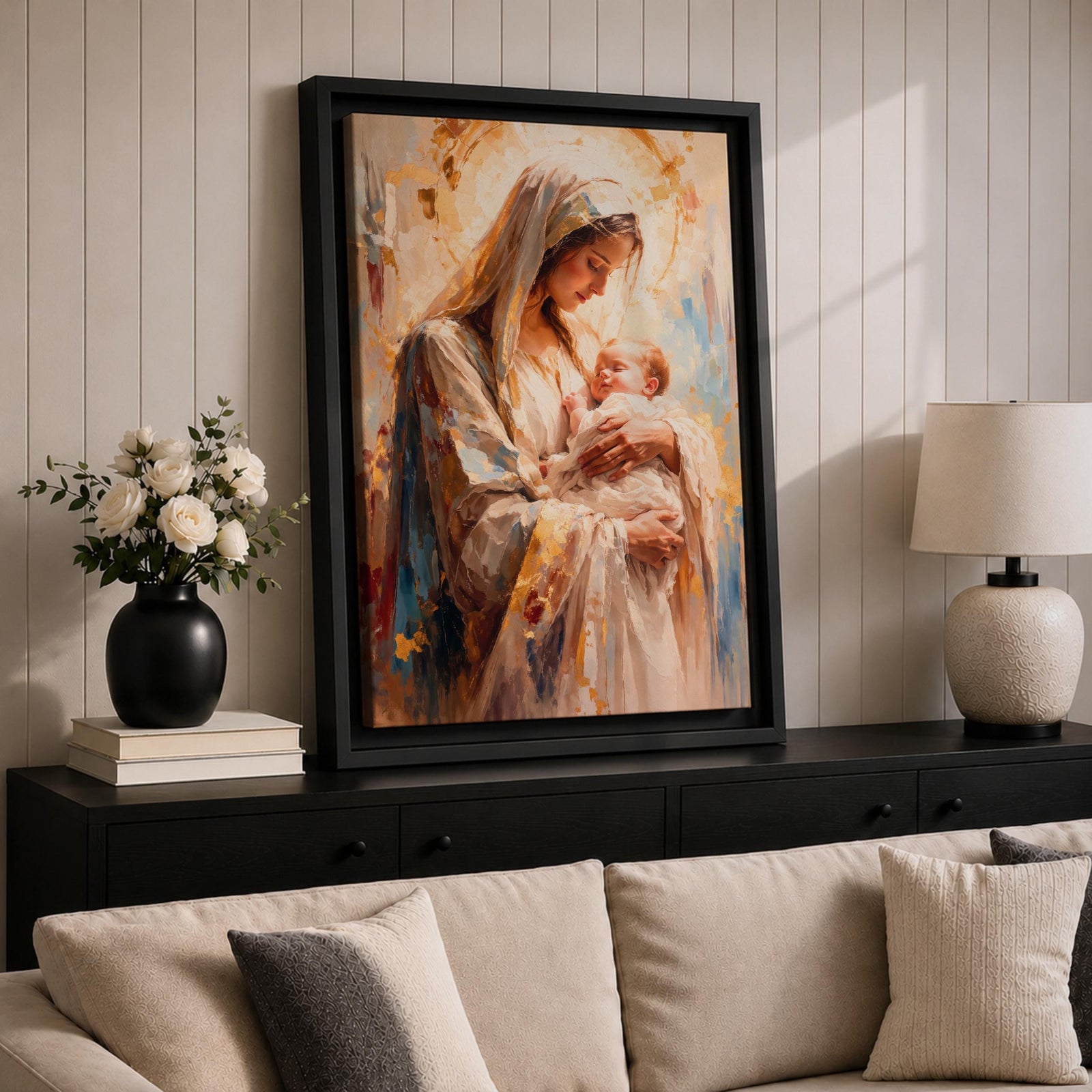 A framed canvas painting depicting Madonna and Child, showing the Virgin Mary tenderly holding baby Jesus. The artwork features soft brush strokes and warm tones, emphasizing the loving bond between mother and child in a classical religious style.