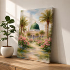 Framed canvas wall art of the Prophet’s Mosque in Medina featuring the iconic green dome, surrounded by palm trees and blooming pink flowers along a sunlit garden path, creating a peaceful and serene Islamic landscape scene for home decor.