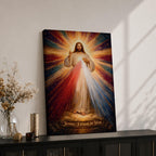 A radiant depiction of Divine Mercy of Jesus shows Jesus standing with one hand raised in blessing and the other pointing to his heart, from which red and pale rays emanate. The figure is surrounded by vibrant rays of light, rendered in a classical religious art style on canvas.