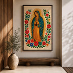 A framed stitched style art print depicting Our Lady of Guadalupe with hands clasped in prayer, surrounded by a radiant golden halo and vibrant floral embroidery in red, blue, and green. The image captures the traditional Mexican Catholic iconography with intricate textile detail and a serene expression.