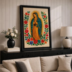 A framed stitched style art print depicting Our Lady of Guadalupe with hands clasped in prayer, surrounded by a radiant golden halo and vibrant floral embroidery in red, blue, and green. The image captures the traditional Mexican Catholic iconography with intricate textile detail and a serene expression.