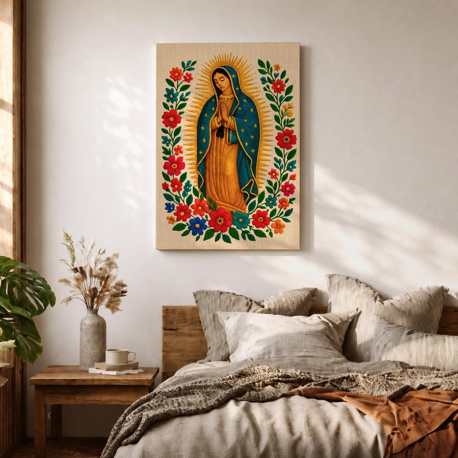 A framed stitched style art print depicting Our Lady of Guadalupe with hands clasped in prayer, surrounded by a radiant golden halo and vibrant floral embroidery in red, blue, and green. The image captures the traditional Mexican Catholic iconography with intricate textile detail and a serene expression.