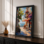 A vibrant Mediterranean café scene featuring a cozy outdoor patio with tables and chairs, colorful flowers cascading from balconies, and a distant view of the sea. The artwork captures a lively coastal atmosphere with impressionistic brushstrokes and rich textures, evoking a warm and inviting cityscape.