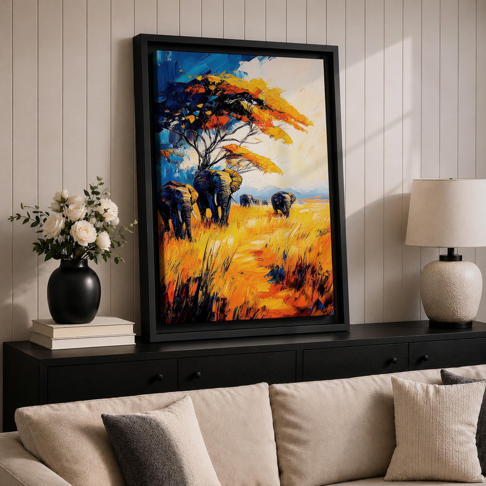A vibrant impasto painting featuring a group of African elephants walking through tall golden grass under a large tree with colorful foliage. The textured brushstrokes emphasize the wildlife subject in a bold and dynamic style with rich blues, oranges, and yellows creating a striking natural scene.