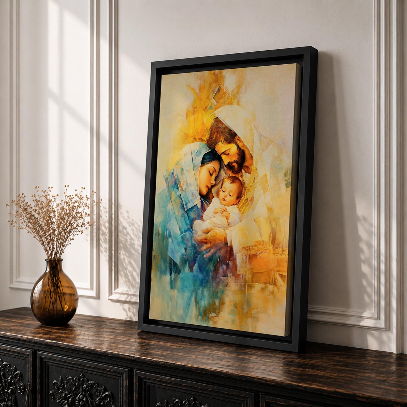 A framed canvas artwork depicting the Holy Family with Mary, Joseph, and baby Jesus in a tender embrace. The painting features warm tones and soft brush strokes, capturing the intimate moment of the Nativity scene with a focus on the figures' expressions and clothing details.