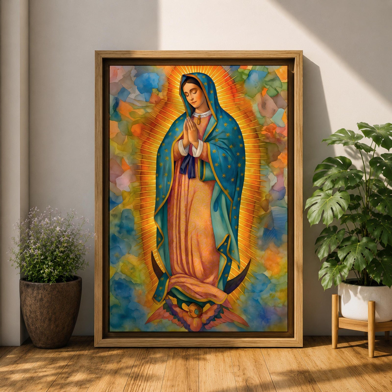 A vibrant framed canvas depicting Our Lady of Guadalupe, showing the Virgin Mary with hands clasped in prayer, wearing a blue mantle adorned with stars and a pink dress, surrounded by radiant golden rays and a colorful abstract background.