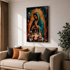 A vibrant framed canvas painting of Our Lady of Guadalupe depicts the Virgin of Guadalupe with hands clasped in prayer, wearing a teal mantle adorned with gold stars and surrounded by radiant light. The foreground features a colorful array of flowers, emphasizing the Catholic religious theme.