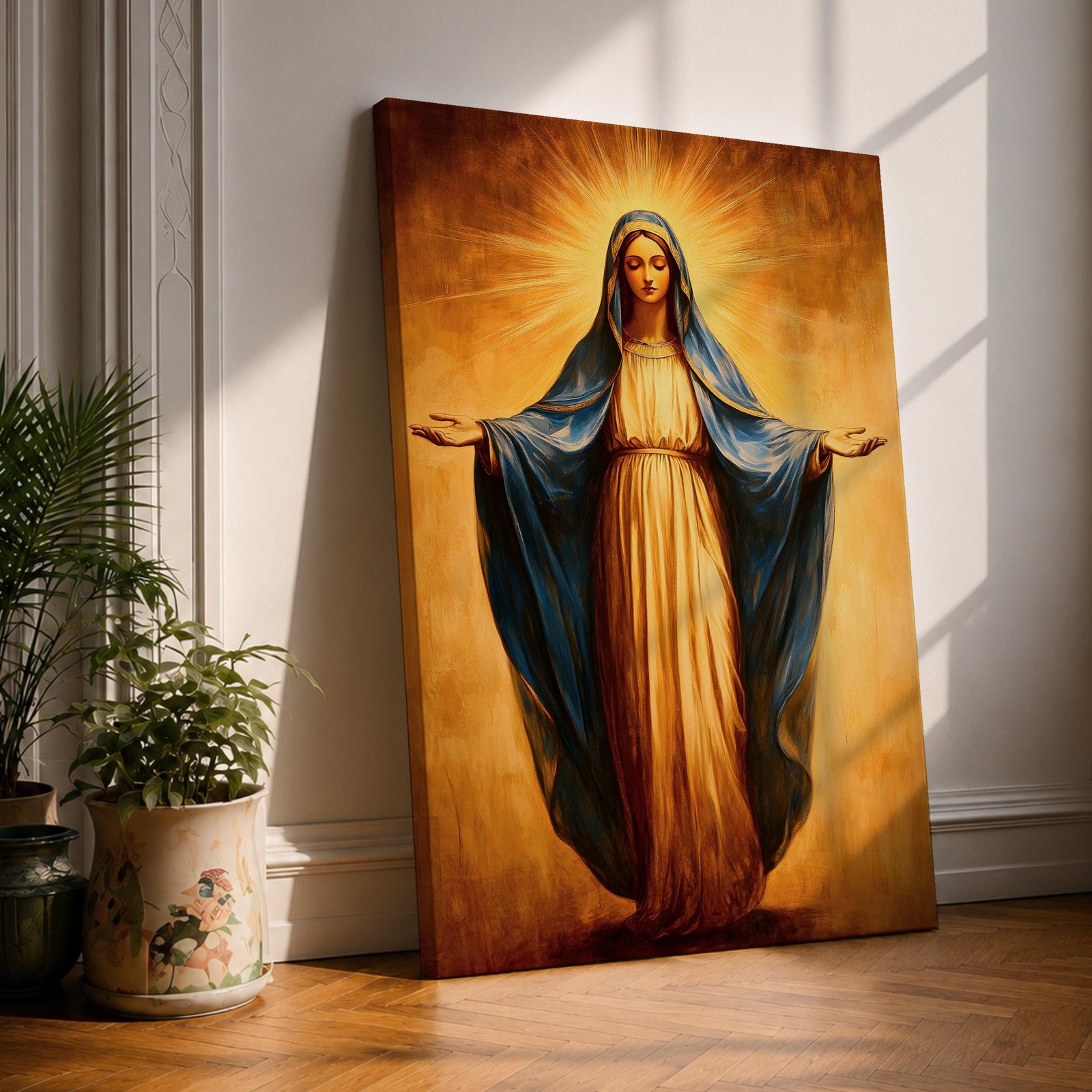 A vintage-style framed canvas painting of Our Lady of Grace depicts the Virgin Mary standing with open arms and a radiant halo behind her head. She wears a flowing robe with a blue mantle, rendered in warm tones and classic religious art style, emphasizing serenity and grace.