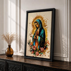 A detailed framed canvas print depicting Our Lady of Guadalupe with hands clasped in prayer, wearing a blue mantle and surrounded by a golden aura and pink roses, rendered in a vibrant, illustrative style emphasizing cultural and religious symbolism.
