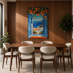 A vibrant framed canvas painting depicting an open Mediterranean-style window with blue shutters overlooking a coastal landscape. Above the window, ripe orange fruits hang from branches, framing a scenic view of white houses with terracotta roofs and a deep blue sea under a clear sky, rendered in a vivid, realistic style.