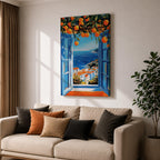 A vibrant framed canvas painting depicting an open Mediterranean-style window with blue shutters overlooking a coastal landscape. Above the window, ripe orange fruits hang from branches, framing a scenic view of white houses with terracotta roofs and a deep blue sea under a clear sky, rendered in a vivid, realistic style.