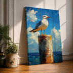 A framed canvas painting of a seagull perched on a weathered post against a bright blue sky with fluffy clouds and a distant ocean horizon. The artwork captures the bird in a realistic style with textured brushstrokes emphasizing the natural coastal scene.