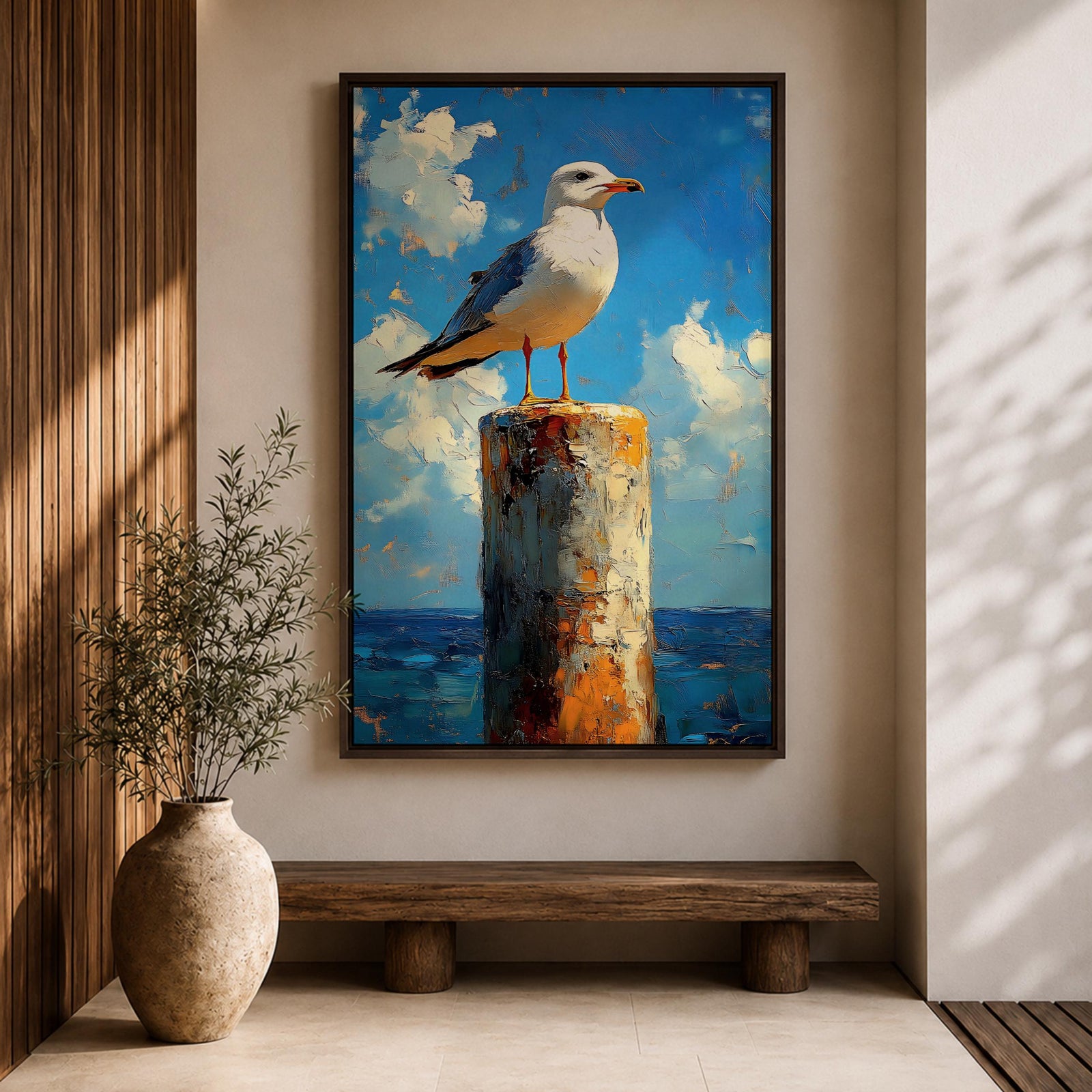 A framed canvas painting of a seagull perched on a weathered post against a bright blue sky with fluffy clouds and a distant ocean horizon. The artwork captures the bird in a realistic style with textured brushstrokes emphasizing the natural coastal scene.
