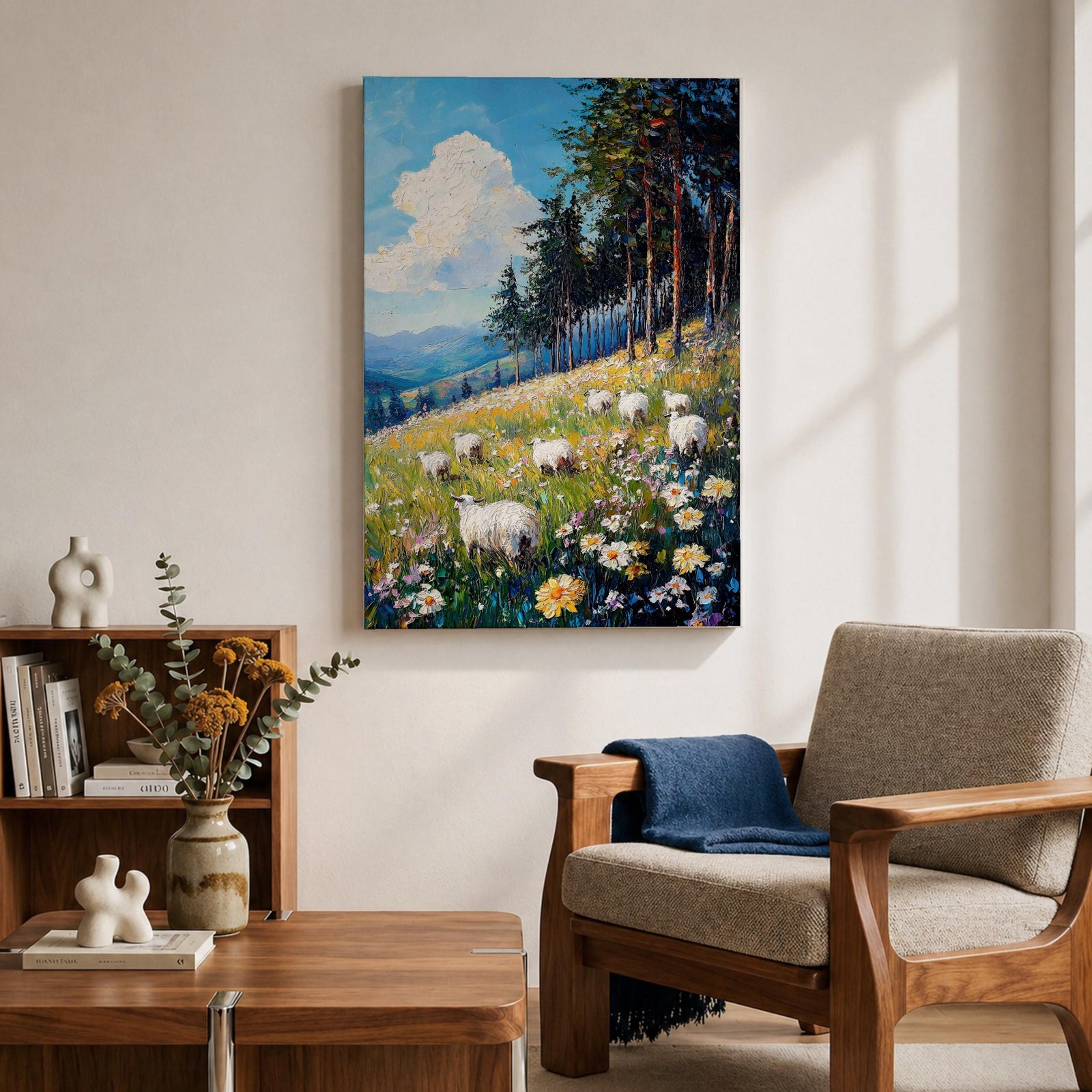 This impasto style framed canvas depicts a scenic landscape of sheep grazing in a meadow filled with wildflowers, bordered by tall trees and distant mountains under a bright blue sky with fluffy clouds, rendered with thick textured brushstrokes that emphasize the natural rustic setting.