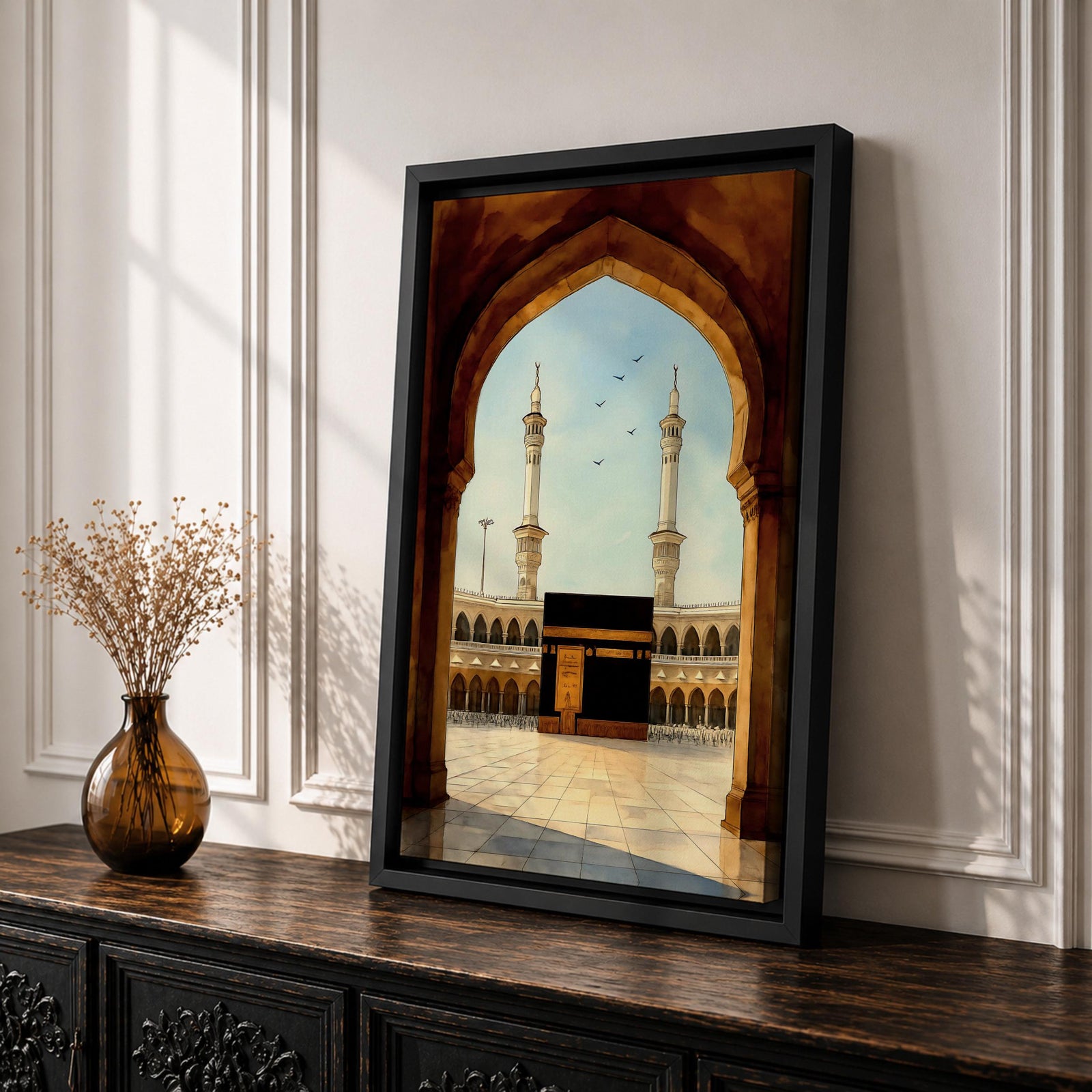 A watercolor style framed canvas depicting the Kaaba viewed through an arched gateway, showing the black cube structure with golden door and surrounding mosque minarets under a clear sky with flying birds, rendered in warm tones and detailed architectural elements.
