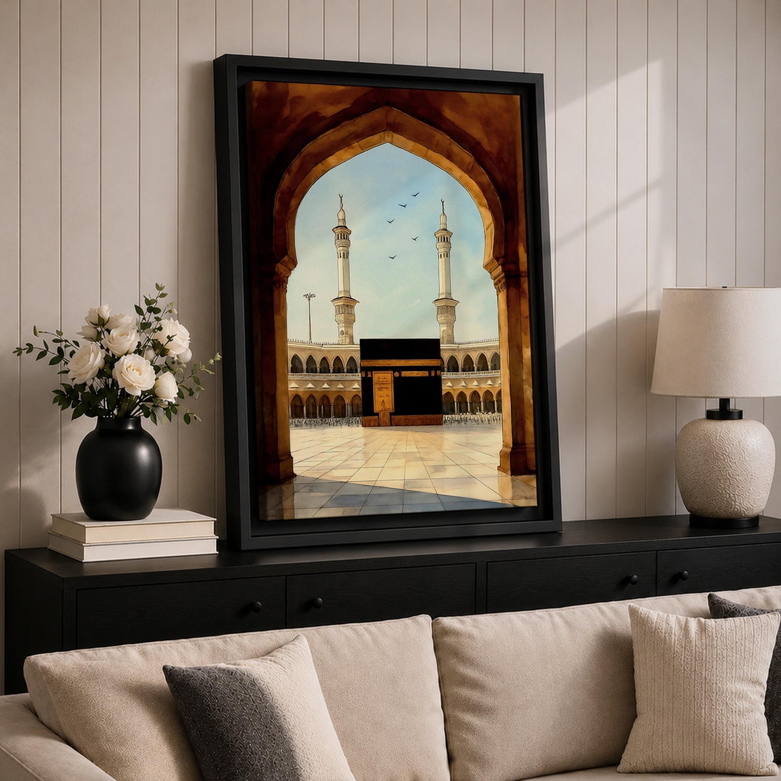 A watercolor style framed canvas depicting the Kaaba viewed through an arched gateway, showing the black cube structure with golden door and surrounding mosque minarets under a clear sky with flying birds, rendered in warm tones and detailed architectural elements.
