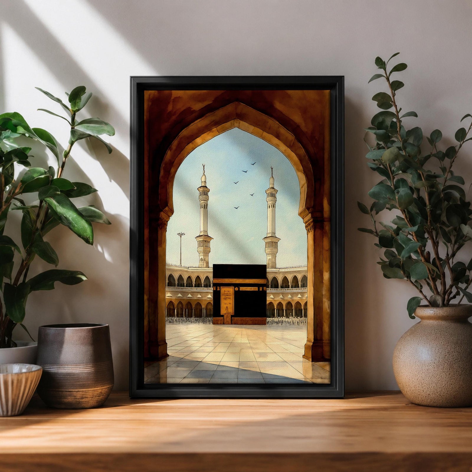 A watercolor style framed canvas depicting the Kaaba viewed through an arched gateway, showing the black cube structure with golden door and surrounding mosque minarets under a clear sky with flying birds, rendered in warm tones and detailed architectural elements.