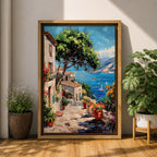 This artwork depicts a vibrant Italian village scene with terracotta-roofed houses, lush greenery, and colorful flowers lining a stone pathway that leads down to a bright blue Mediterranean sea with sailboats and distant mountains, rendered in a realistic style capturing coastal charm.