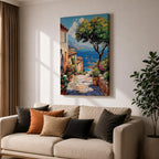 A vibrant framed canvas painting depicting a charming coastal village with stone-paved streets, terracotta rooftops, lush greenery, colorful flowers, and sailboats on a deep blue sea under a clear sky, rendered in a detailed, realistic style capturing Mediterranean summer ambiance.