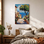 A vibrant framed canvas painting depicting a charming coastal village with stone-paved streets, terracotta rooftops, lush greenery, colorful flowers, and sailboats on a deep blue sea under a clear sky, rendered in a detailed, realistic style capturing Mediterranean summer ambiance.