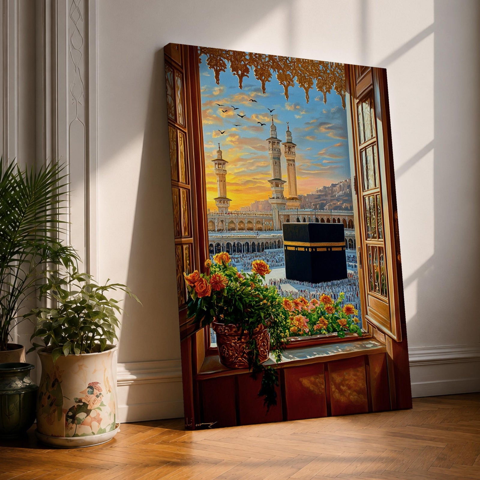 Painting of the Kaaba at Masjid Al Haram in Mecca viewed through an open wooden window with flowers on the sill, showing the black Kaaba in the courtyard surrounded by worshippers and tall mosque minarets under a glowing sunset sky.