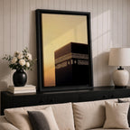 Minimalist artwork of the Kaaba at Masjid Al Haram in Mecca showing the black cubic shrine with gold calligraphy bands against a dramatic golden sunset sky and soft clouds.