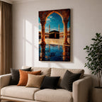 Framed wall art showing the Kaaba at Masjid Al Haram in Mecca viewed through a grand marble archway with columns and reflective courtyard tiles under a bright blue sky.